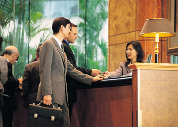 Woman at hotel desk checking in guests